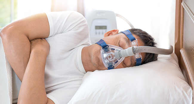 Hombre dormido con un CPAP (tratamiento para la apnea del sue�o).