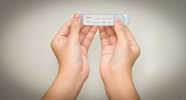 Persona sosteniendo un brazalete de hospital.