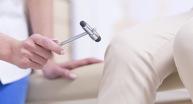 Neur�logo examinando reflejos de paciente.