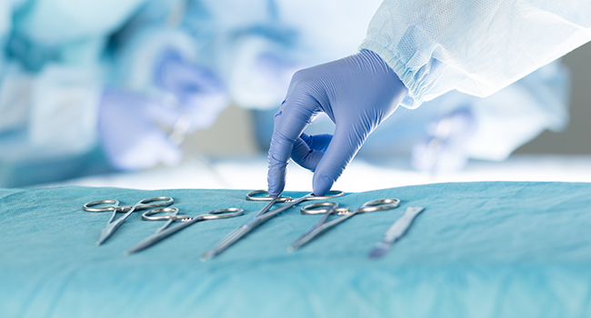 Manos con guantes agarrando pinzas para cirugía